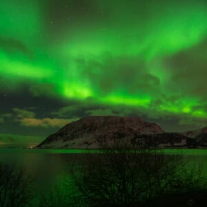 Green aurora arcing over a dark island at Nupen, Kvæfjord
