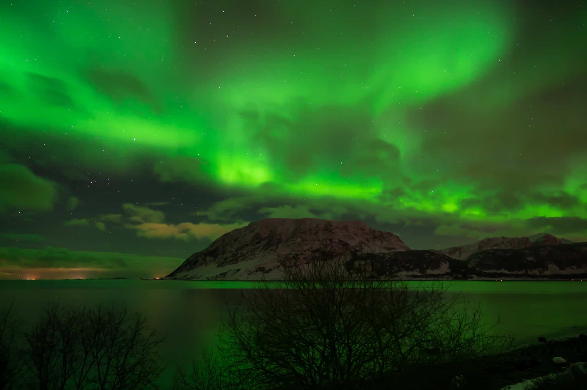 Green aurora arcing over a dark island at Nupen, Kvæfjord