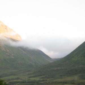 Cloud wrapping a mountain summit above steep green slopes