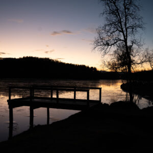 A weathered jetty and its reflection in calm water at twilight