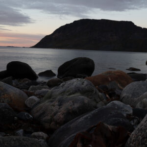 Dusk settling over a boulder beach and a distant mountain island