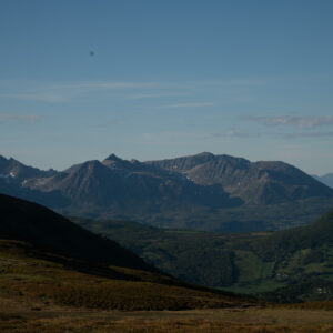 Layered green mountains rising to a jagged range beyond