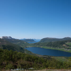 Mountain lake and distant fjord seen from a green summit ridge