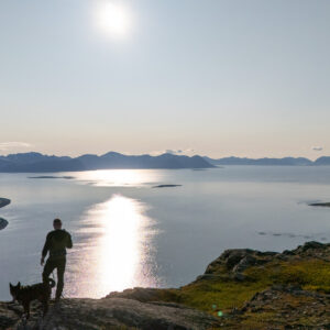 A hiker and dog on a moonlit summit at Keipen, Grytøya