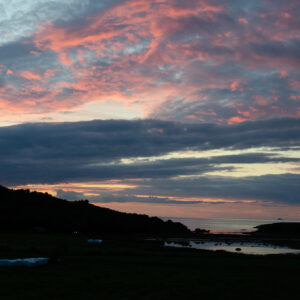 Rose-coloured clouds burning above a dark fjord and shoreline
