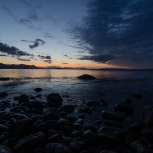 A stony arctic beach at dusk with cloud banks on the horizon