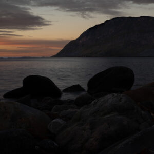 Rounded stones and calm sea beneath a fading evening sky