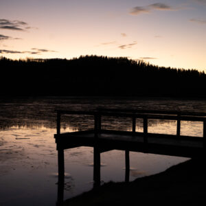 Wooden pier on a glass-calm lake beneath silhouetted trees