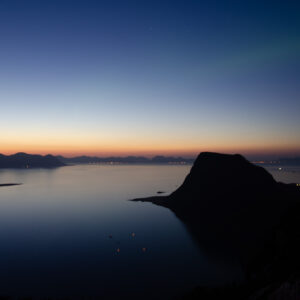 Calm arctic sea and layered headlands under a cold blue sky