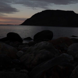 Smooth shoreline boulders under soft twilight over a northern island