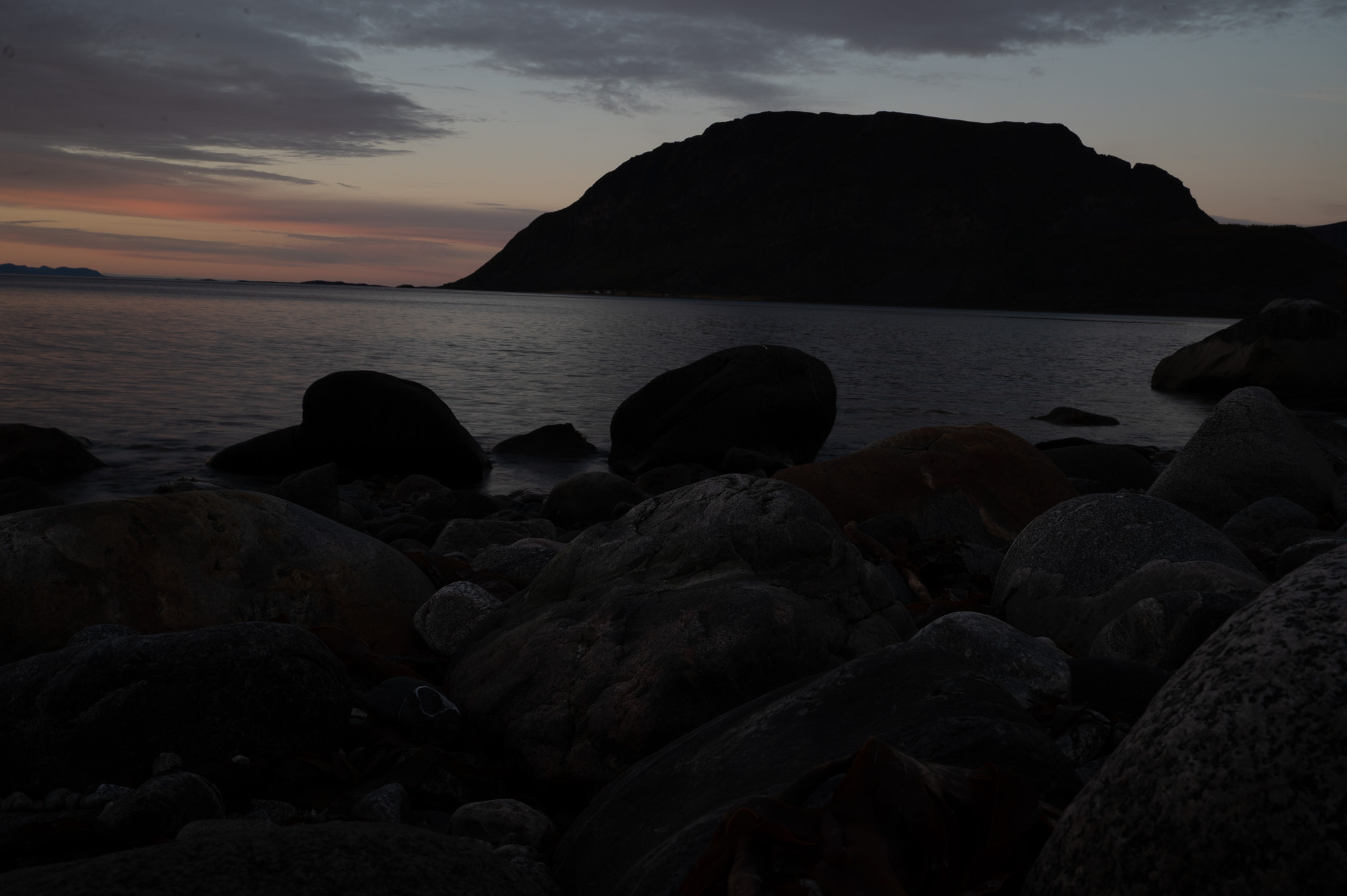 Smooth shoreline boulders under soft twilight over a northern island