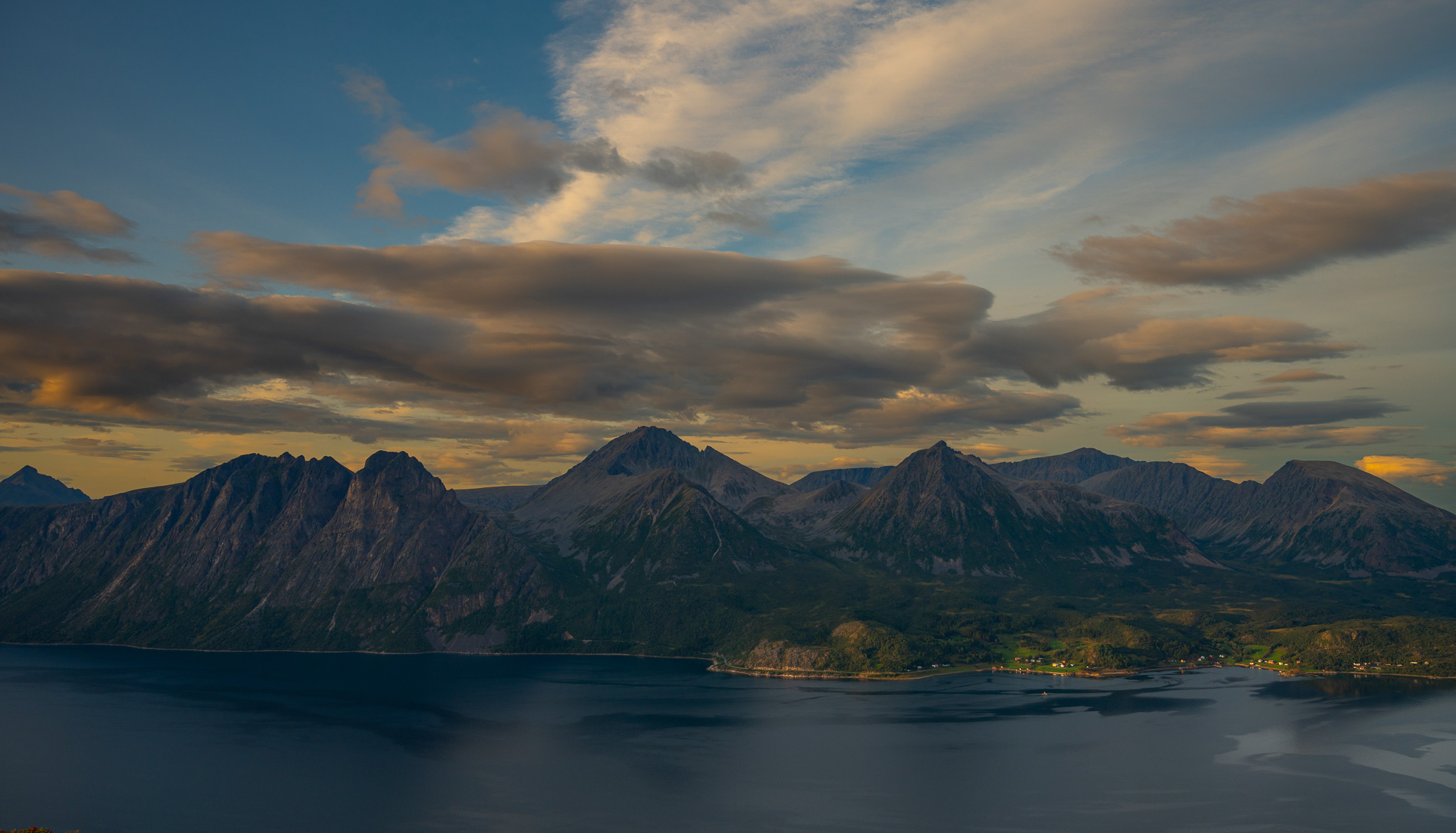 High cirrus clouds drawn across the sky above fjord and mountains