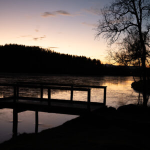 Wooden jetty reaching into a mirror-still lake under a fading sky