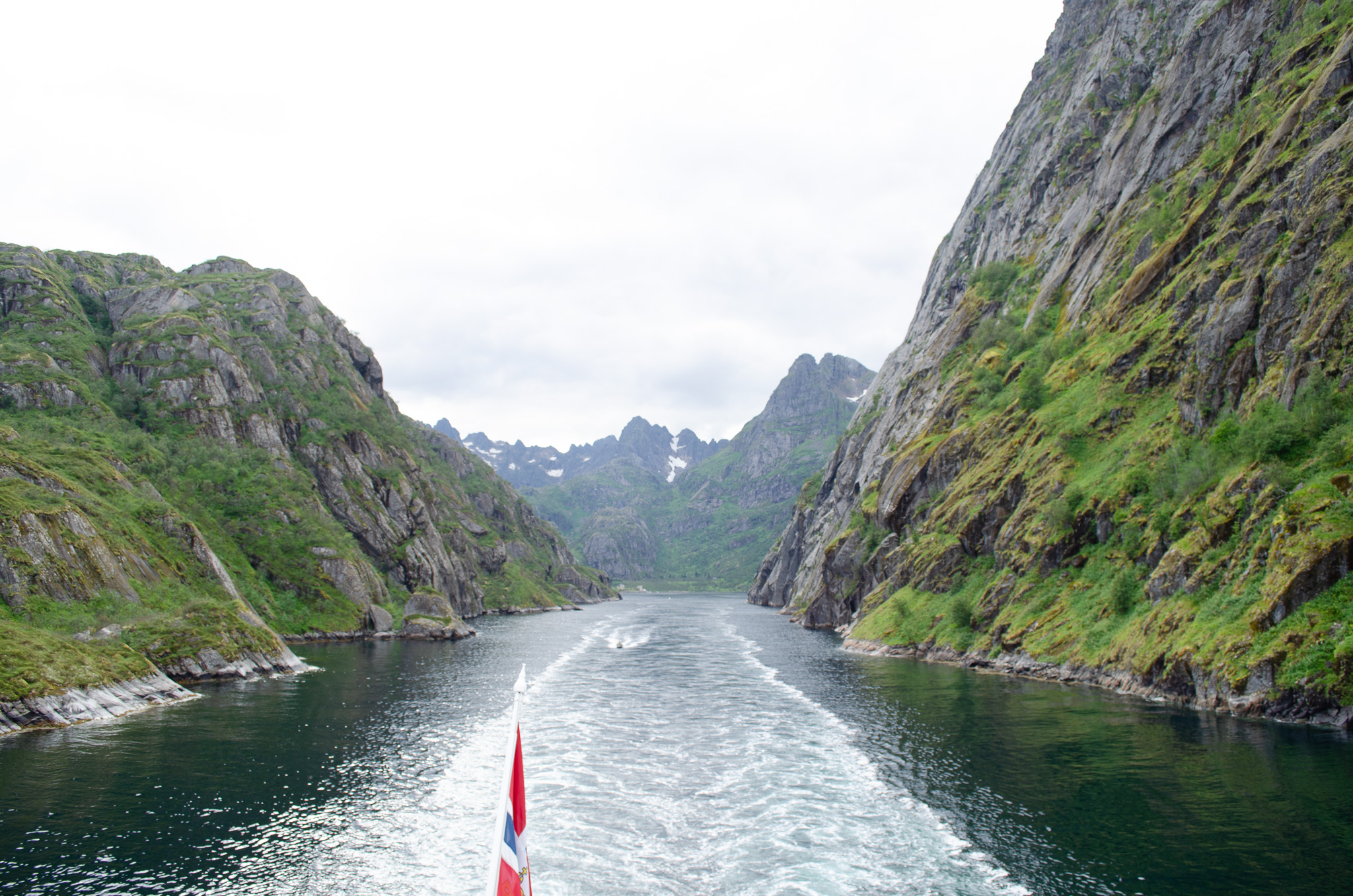 A ship's wake between the steep walls of a narrow Norwegian fjord